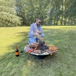 homme prépare barbecue sur grand brasero fonte et sa plancha