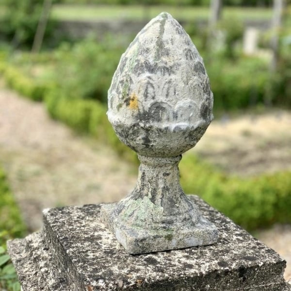 pigne de pin posée sur un pilier en pierre en extérieur