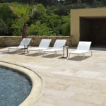 Dallage pierre naturelle beige Castel au bord d'une piscine dans un jardin moderne