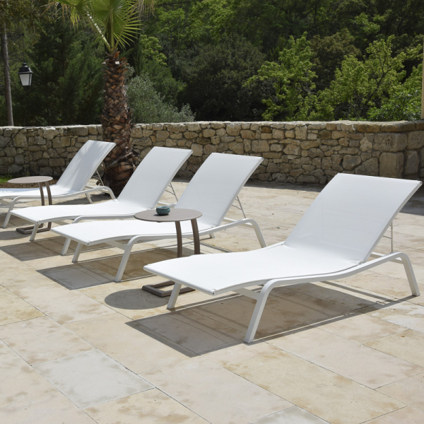 Dalles Castel Dallage pierre naturelle beige Castel avec des chaises longues blanches dans un jardin moderne