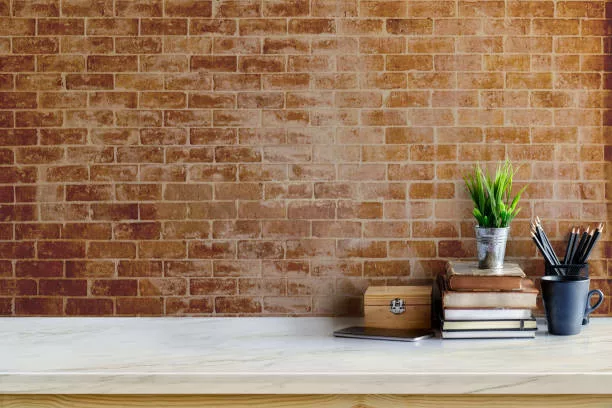 Bureau avec des accéssoires sur une table de travail et mur en parement brique en fond