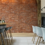 Mur de brique dans une salle à manger avec des chaises blanches et grises