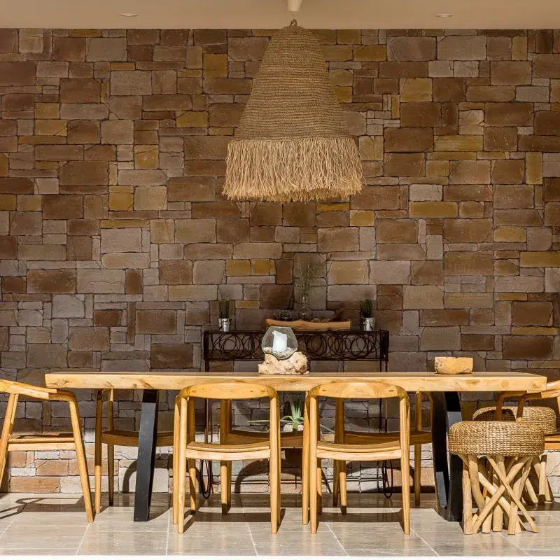 Table à manger extérieur en bois avec un parement mural en pierre sur tout le mur