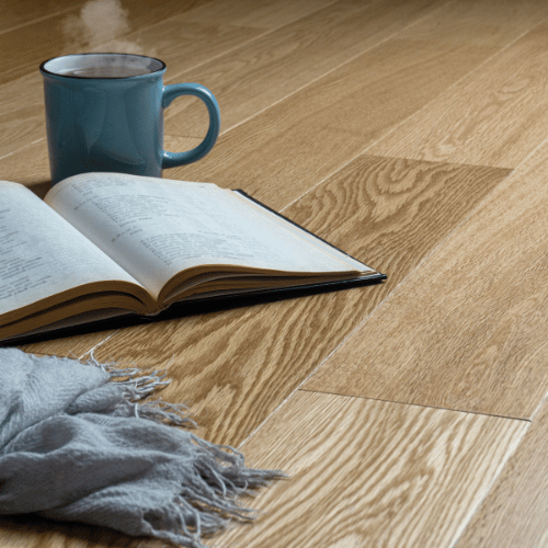 Tasse et livre posés sur un sol en parquet contrecollé