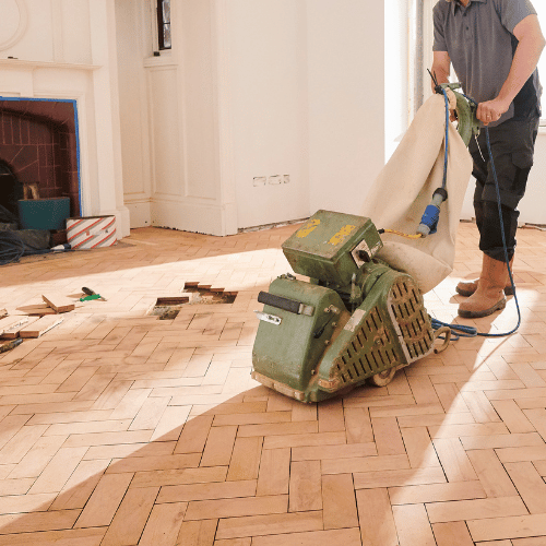 homme ponce parquet contrecollé avec ponceuse électrique